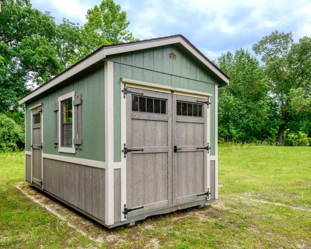 Green painted carriage house portable storage building with double barn doors