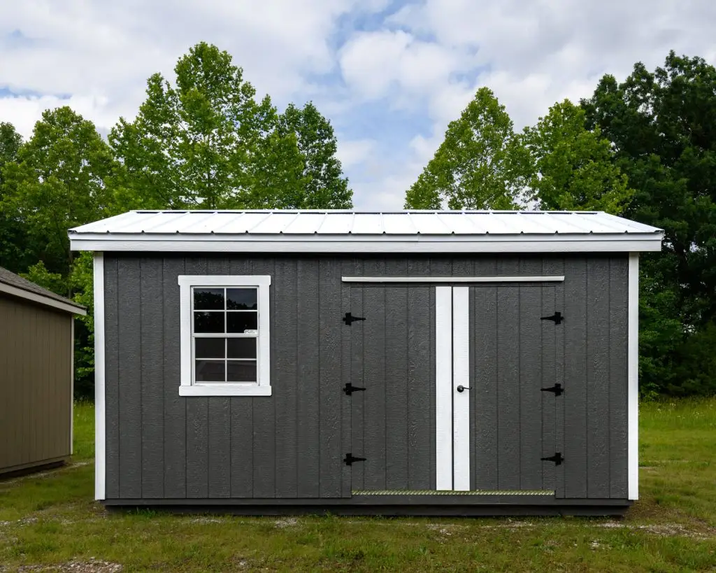 Gray painted cabin with single window and double barn door.